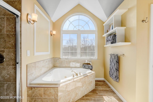 bathroom with wood tiled floor, vaulted ceiling, a shower stall, a jetted tub, and baseboards