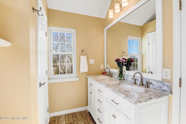 bathroom featuring wood tiled floor, a sink, baseboards, and double vanity