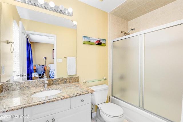 full bath with shower / bath combination with glass door, vanity, toilet, and ensuite bathroom