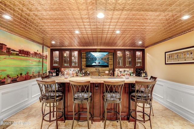 bar featuring a wainscoted wall, an ornate ceiling, wet bar, and recessed lighting