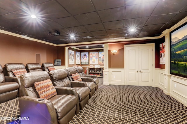 carpeted cinema room featuring recessed lighting, ornamental molding, a decorative wall, and wainscoting