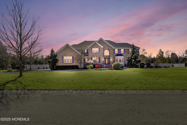 view of front of home featuring brick siding, a front yard, and fence