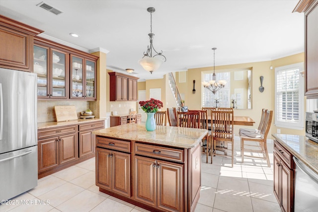 kitchen with light tile patterned flooring, backsplash, freestanding refrigerator, and crown molding