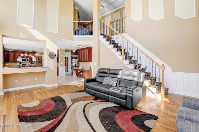 living room featuring light wood-type flooring, a notable chandelier, and stairs