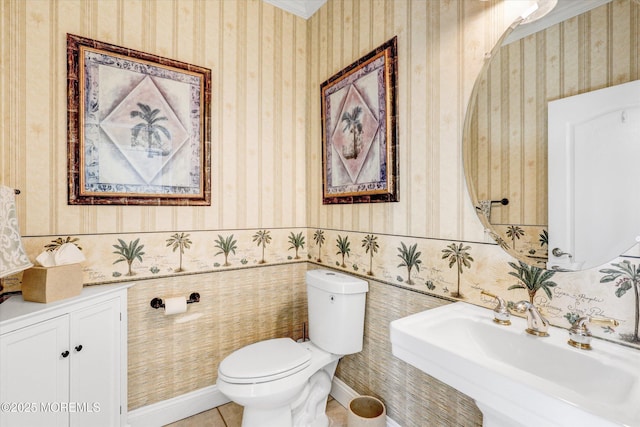 half bathroom with wallpapered walls, baseboards, toilet, tile patterned flooring, and a sink