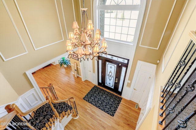 foyer featuring a high ceiling, stairway, wood finished floors, and a notable chandelier