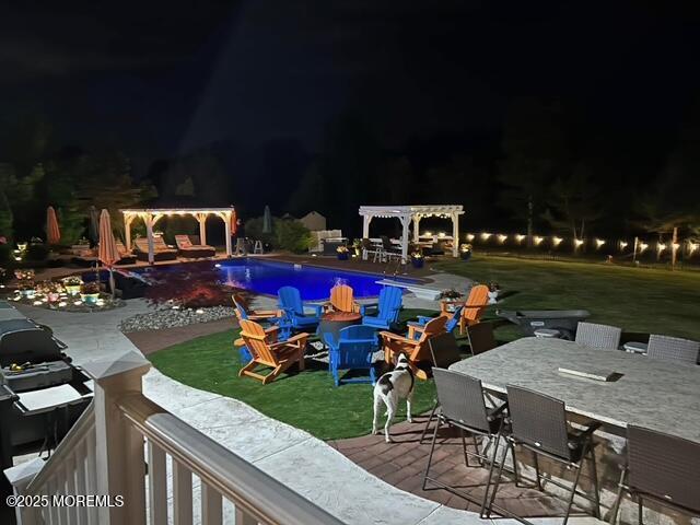 pool at twilight featuring a yard, an outdoor pool, a patio, and a pergola