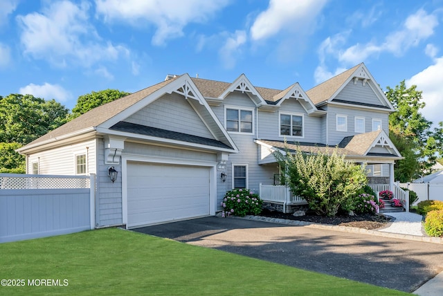 view of front of home featuring a garage, driveway, a front lawn, and fence