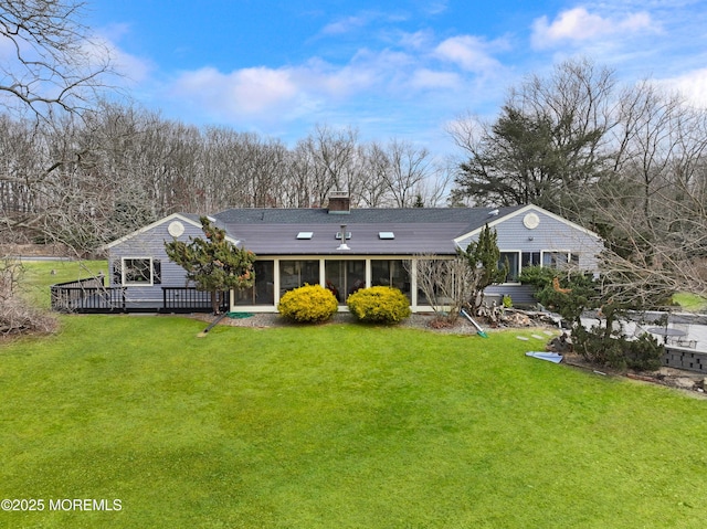 rear view of house with a lawn and a sunroom