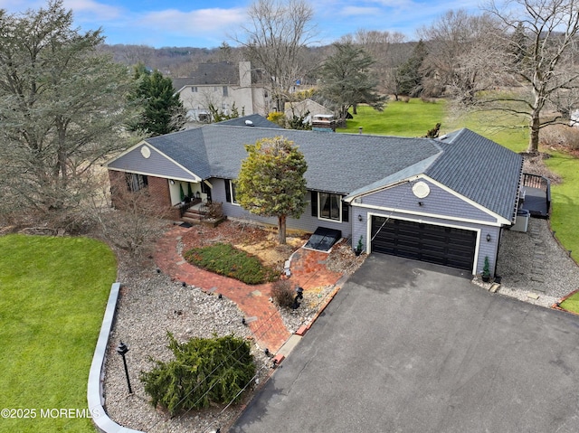 single story home with a front yard, a garage, driveway, and a shingled roof