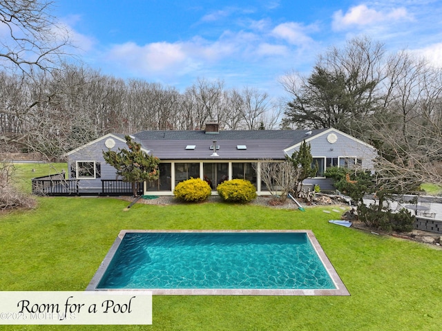 back of house featuring a deck, a lawn, an outdoor pool, and a sunroom