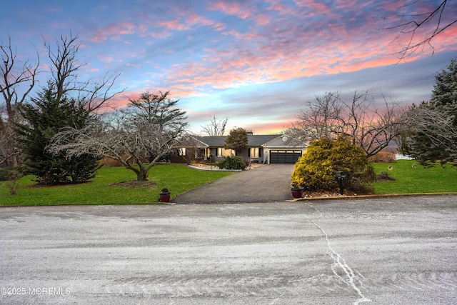 view of front of home featuring aphalt driveway, an attached garage, and a front yard