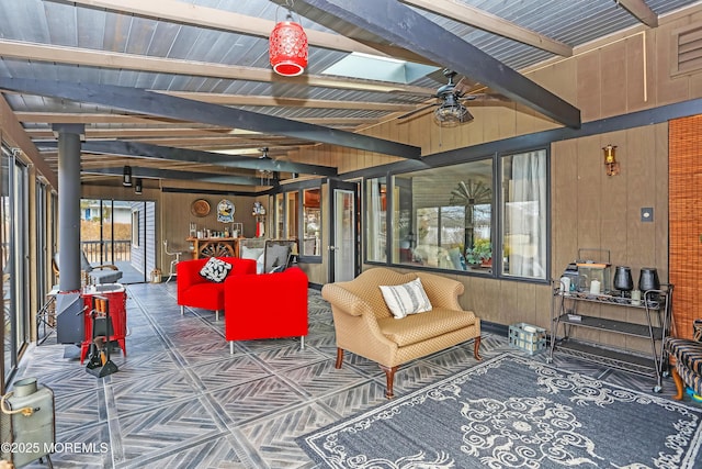 sunroom featuring beamed ceiling and a ceiling fan