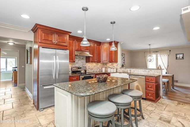 kitchen with a peninsula, stone tile floors, under cabinet range hood, and stainless steel appliances