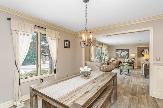 dining space featuring light wood-style flooring, crown molding, and an inviting chandelier