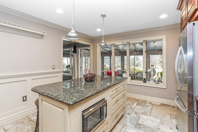 kitchen with ornamental molding, cream cabinetry, appliances with stainless steel finishes, and stone tile flooring