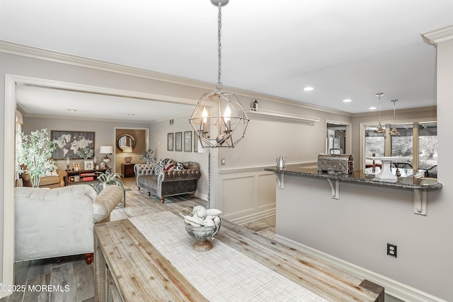 dining area with light wood-style flooring, recessed lighting, ornamental molding, wainscoting, and a decorative wall