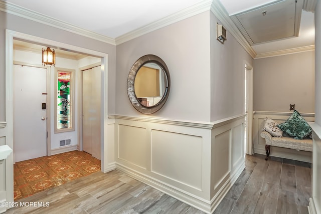 entrance foyer featuring visible vents, ornamental molding, and light wood finished floors