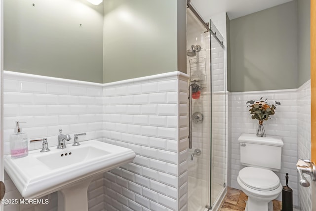 full bath featuring toilet, tile walls, a stall shower, and wainscoting