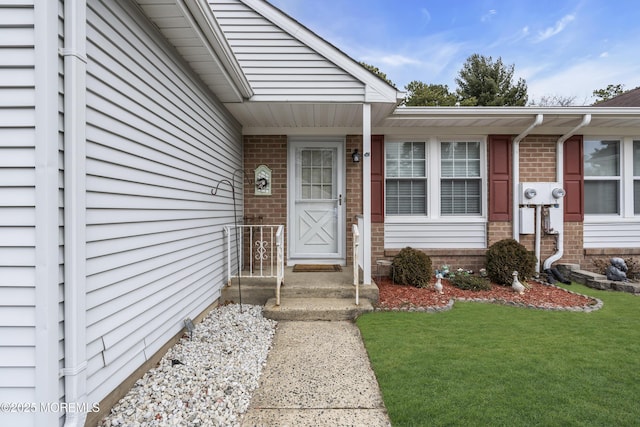 doorway to property featuring brick siding and a yard