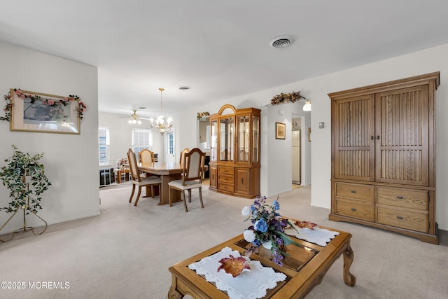 living area featuring light colored carpet, visible vents, and an inviting chandelier