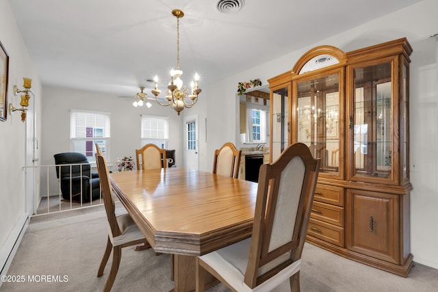 dining room featuring a chandelier, a baseboard radiator, light carpet, and visible vents