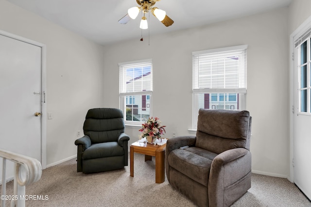 living area with carpet, baseboards, and a ceiling fan