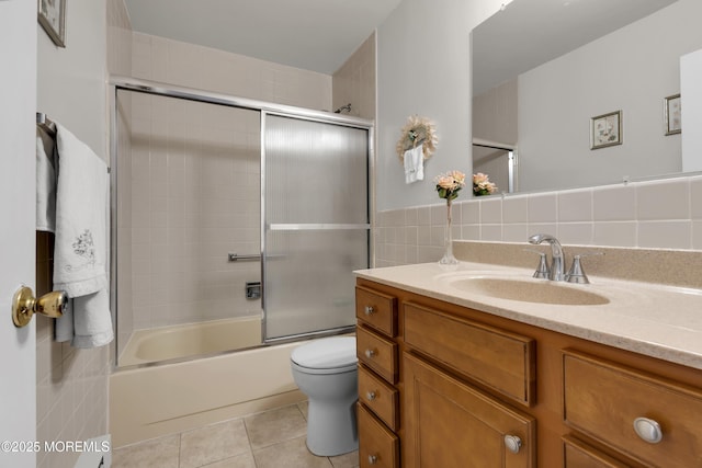 full bathroom featuring tile walls, toilet, combined bath / shower with glass door, vanity, and tile patterned flooring