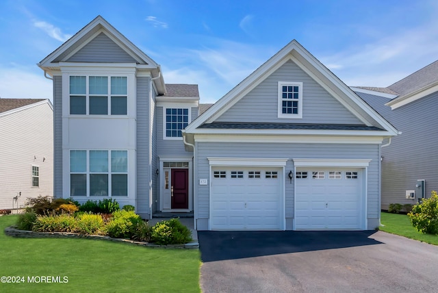 traditional home with a garage, aphalt driveway, a front yard, and a shingled roof