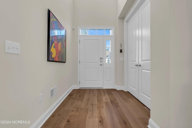 foyer with wood finished floors, visible vents, and baseboards