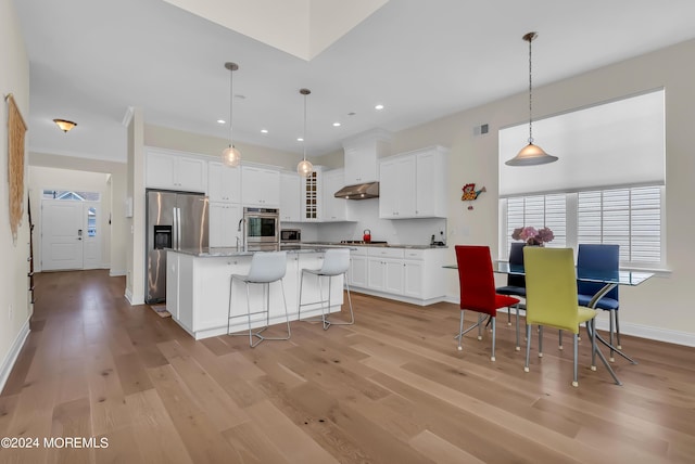 kitchen with stainless steel appliances, white cabinetry, under cabinet range hood, and light wood finished floors