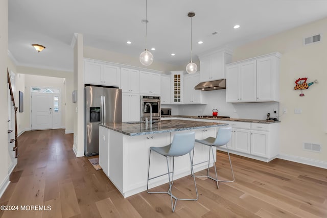 kitchen with stainless steel appliances, visible vents, light wood-style flooring, and under cabinet range hood