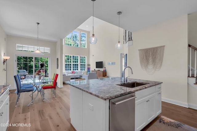 kitchen featuring light stone counters, light wood-type flooring, a sink, and dishwasher