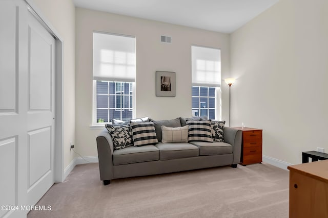 living area with baseboards, visible vents, and light colored carpet