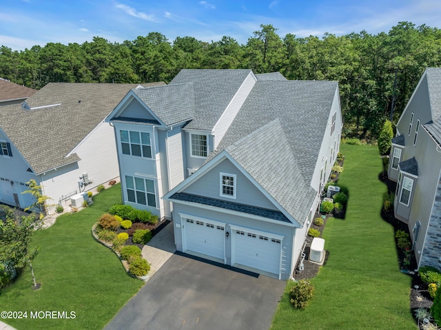 view of front of home featuring roof with shingles, driveway, and a front lawn