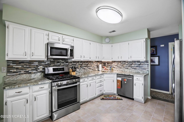 kitchen featuring white cabinets, visible vents, stainless steel appliances, and backsplash