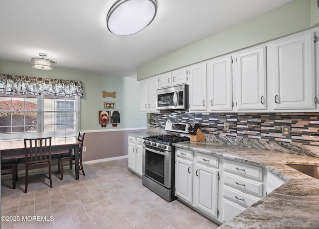 kitchen with appliances with stainless steel finishes, white cabinetry, and backsplash