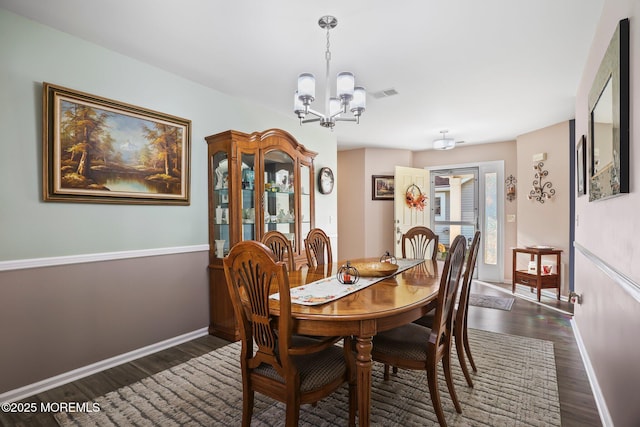 dining area featuring dark wood-type flooring, an inviting chandelier, visible vents, and baseboards