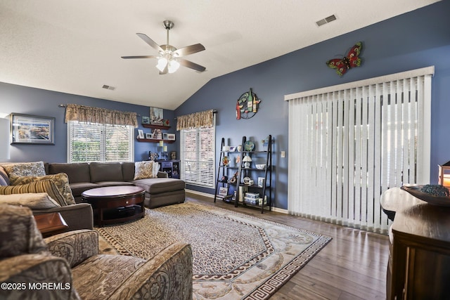 living area with vaulted ceiling, wood finished floors, visible vents, and a ceiling fan