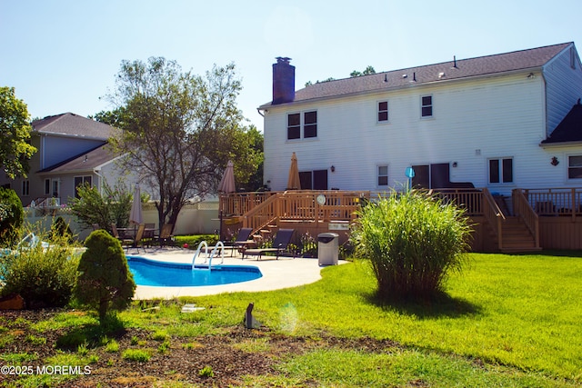 rear view of house featuring a patio, a fenced in pool, a wooden deck, a chimney, and a lawn