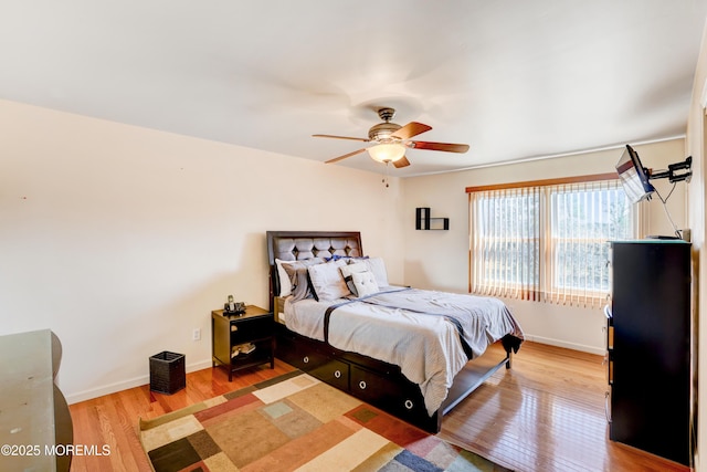 bedroom featuring baseboards, wood finished floors, and a ceiling fan