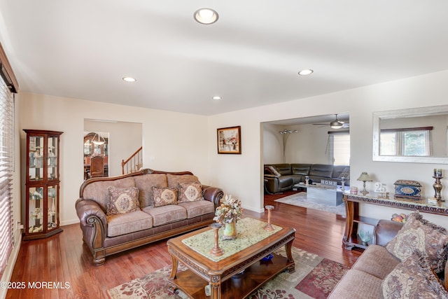 living room featuring a ceiling fan, wood finished floors, baseboards, recessed lighting, and stairs