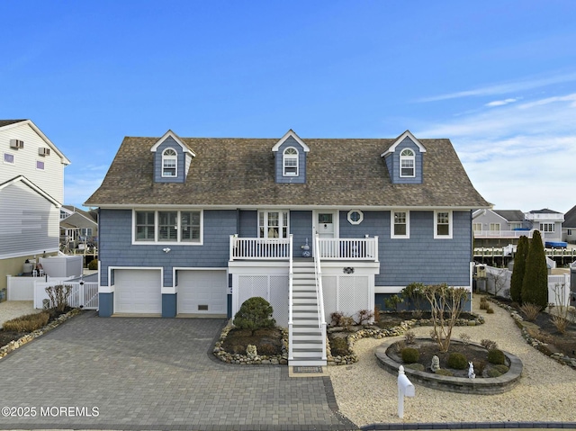 view of front of home with a porch, an attached garage, fence, stairs, and decorative driveway