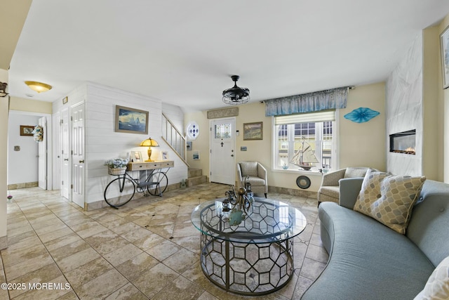 living room featuring stairs, a high end fireplace, and baseboards