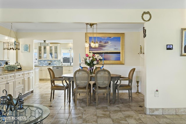 dining space featuring ornamental molding and a wainscoted wall