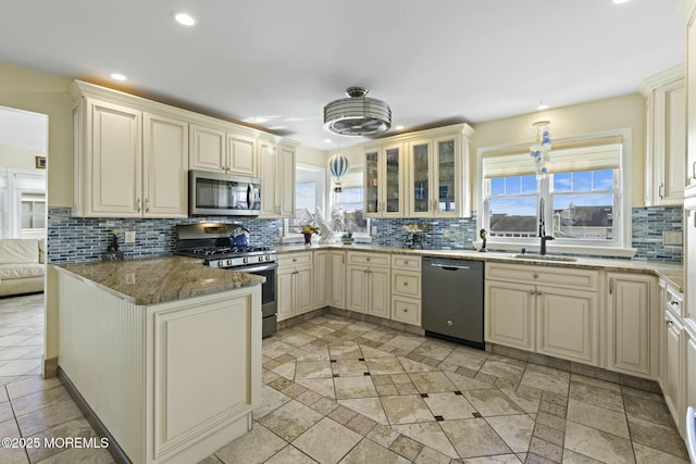 kitchen featuring stainless steel appliances, cream cabinets, a sink, and a wealth of natural light