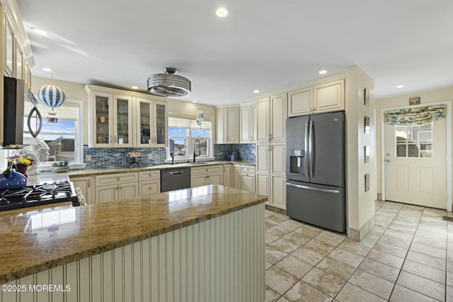 kitchen with cream cabinetry, stainless steel refrigerator with ice dispenser, backsplash, dishwasher, and a peninsula