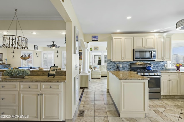 kitchen with appliances with stainless steel finishes, cream cabinetry, decorative backsplash, ornate columns, and crown molding