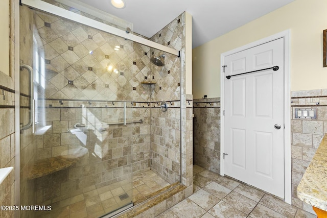 bathroom with a shower stall, tile walls, and wainscoting