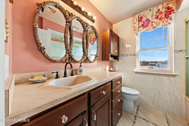 bathroom with tile walls, plenty of natural light, vanity, and toilet